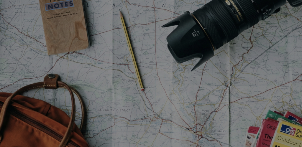 Flat lay of a travel map, camera, notebook, and bag representing solo travel planning and independent exploration