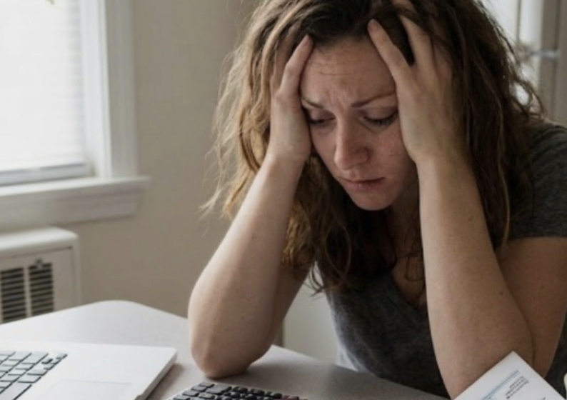 Single woman stressed about finances calculating expenses illustrating the singles tax burden